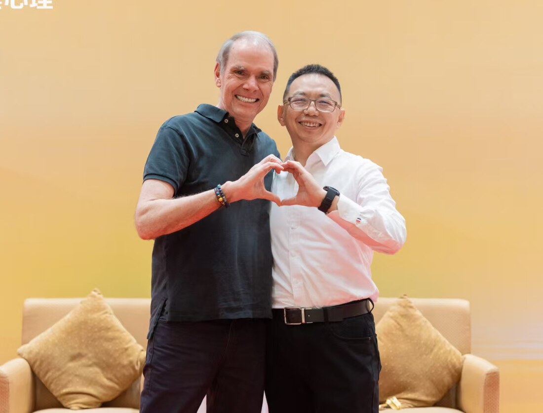 Jacky Lee Li Chong with Robert Dilts, forming a heart gesture